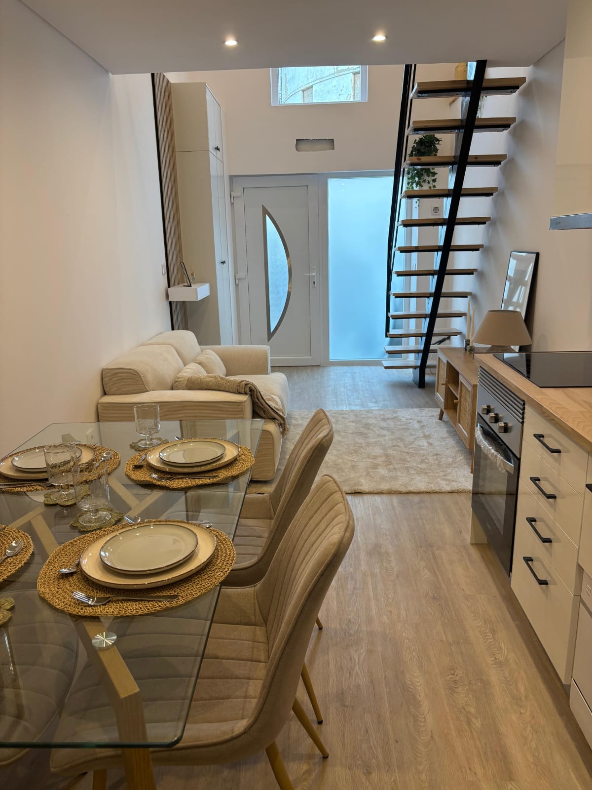 Sala e jantar em espaço aberto, com mesa em vidro e escada em madeira